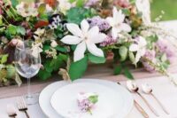 a lush spring wedding tablescape with a catchy and dimensional floral centerpiece, elegant plates and cutlery
