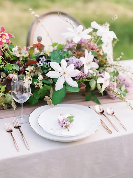 a lush spring wedding tablescape with a catchy and dimensional floral centerpiece, elegant plates and cutlery