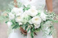 a lush wedding bouquet of greenery and white blooms with ribbons is classics that always works