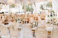a luxurious formal wedding reception with dried greenery over the tables, shiny chandeliers, white blooms in vases
