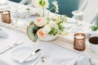 a modern and refined spring wedding table with neutral linens, candles, a catchy floral centerpieces and simple cutlery