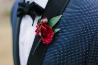 a navy polka dot tux with black lapels, a black bow tie and a bold red bloom and leaves for a lovely and bold touch of color