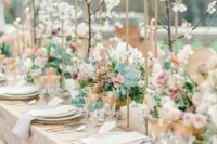 a neutral spring wedding tablescape with blooming branches, floral centerpieces, neutral linens, gold cutlery and gold rimmed glasses