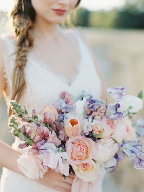 a pastel spring wedding bouquet with peachy and purple blooms for a romantic spring bride