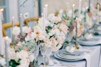 a pastel spring wedding tablescape with dusty blue linens, blush and white blooms and grey candles, candles over the table