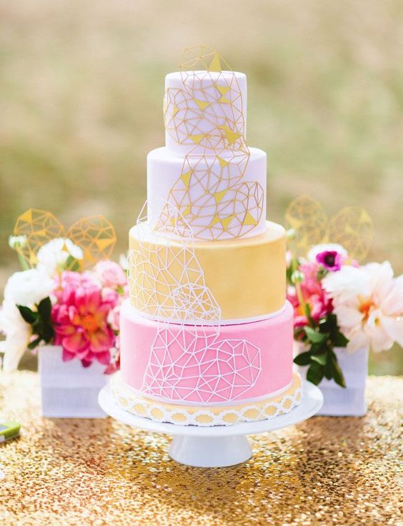a pretty geometric wedding cake with white, yellow and pink tiers and geometric hearts on each tier for a bolder look