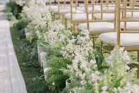 a pretty textural wedding aisle with white blooms and ferns plus pillar candles in glasses is a very elegant idea