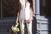 a pure white pantsuit with a sleeveless vest with a plunging neckline and pants, heels and minimalist earrings