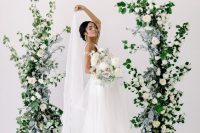 a refined and chic wedding altar of greenery, pale leaves and white roses is super elegant and super chic