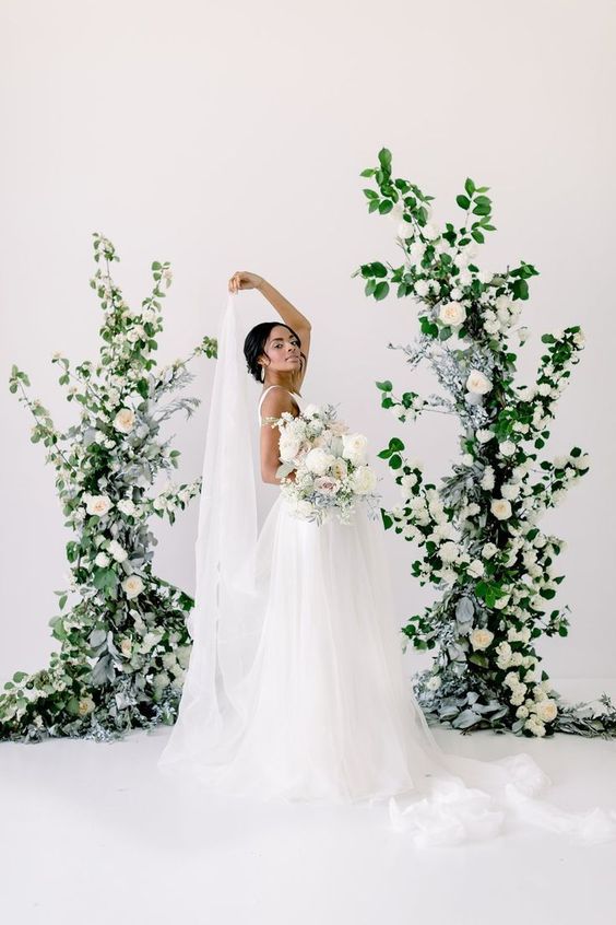 a refined and chic wedding altar of greenery, pale leaves and white roses is super elegant and super chic