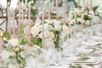 a refined and formal wedding reception with white blooms, blush candles, greenery and elegant white linens