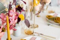 a refined fall wedding tablescape with pink blooms and dark foliage, mustard candles and napkins and some dried grasses