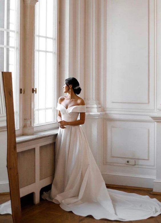 a refined off the shoulder plain A-line wedding dress with a pleated skirt and a train is amazing for a classic wedding