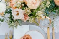 a refined spring wedding table setting with a grey tablecloth and neutral linens, peachy pink blooms and white ones, gold cutlery and glasses