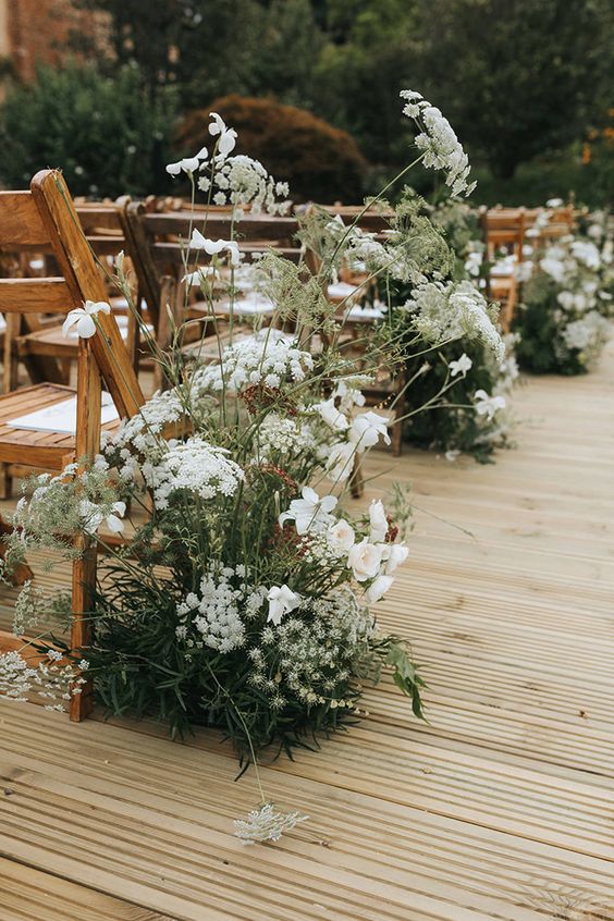 a relaxed summer wedding aisle with white blooms and greenery that look all-natural and fresh, as if they are growing here