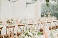 a romantic blush and ivory wedding tablescape with neutral blooms, blush candles, gold cutlery and neutral menus