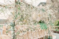 a romantic outdoor blooming wedding reception with lush blooming branches over the table, candles, ivory linens and white chairs