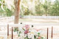 a romantic vintage glam wedding reception with greenery chandeliers, a pastel floral centerpiece and pastel linens