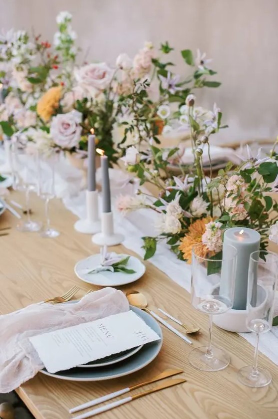 a sophisticated secret garden wedding tablescape with neutral and pastel linens, pastel blooms and greenery, grey candles