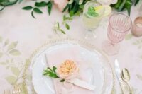 a sophisticated spring wedding table with gold cutlery and sheer plates, a botanical tablecloth, blush and neutral blooms and greenery