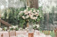 a spring wedding reception with blush linens, tall centerpieces of blush and white blooms and greenery