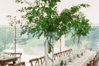 a stylish spring wedding reception with tall greenery centerpieces, white blooms and candles and linens