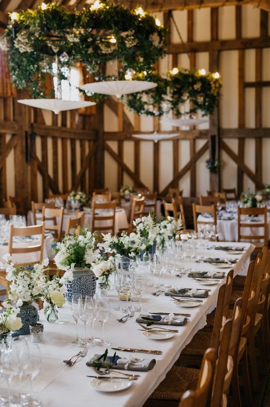 a super elegant barn wedding table with neutral linens, blue vases with white and blue blooms