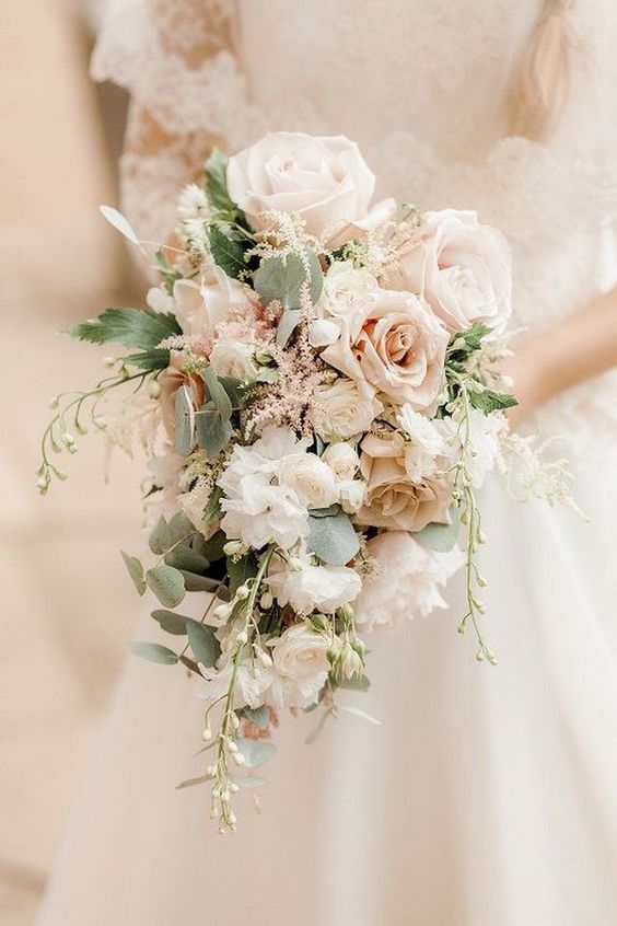 a sweet pastel wedding bouquet with blush and peachy blooms and some pale greenery