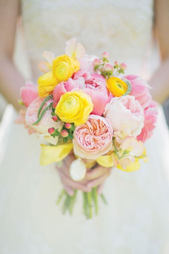 a sweet spring wedding bouquet of lemon yellow ranunculus, pink peonies and peony roses and berries is cool