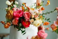a textural and dimensional wedding bouquet of pink, yellow and orange blooms, greenery and textural foliage