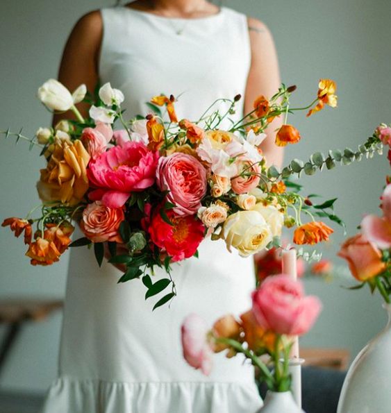 a textural and dimensional wedding bouquet of pink, yellow and orange blooms, greenery and textural foliage