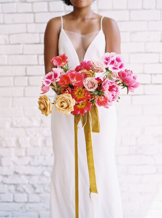 a vibrant wedding bouquet of pink, coral and yellow blooms and mustard ribbons is amazing for summer or fall