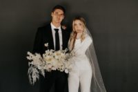 a white pantsuit with cropped pants and a blazer, tan shoes and a long embellished veil for a modern bride