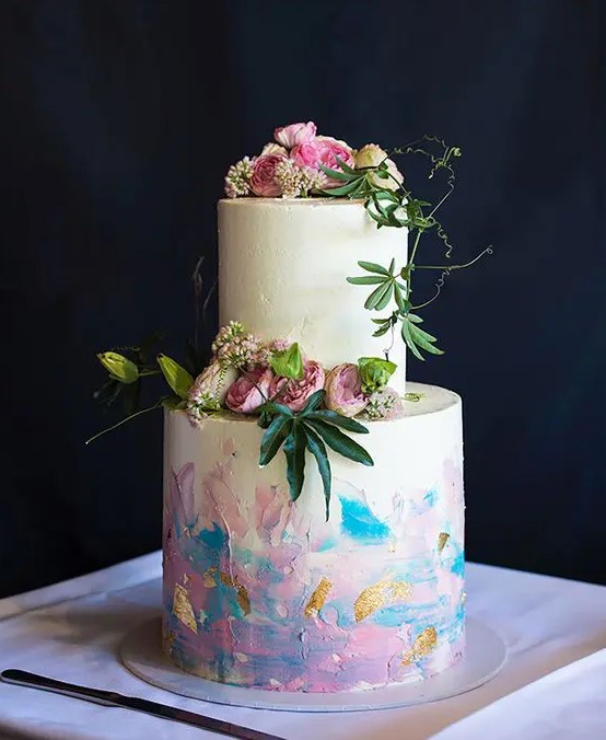 a white wedding cake with iridescent details and gold glitter, with fresh white and pink blooms and greenery