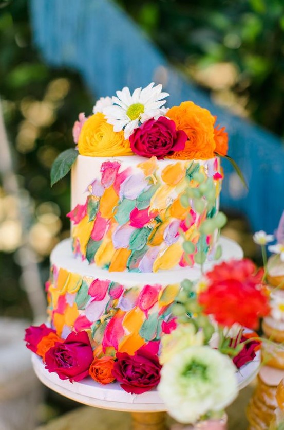 a white wedding cake with super bright textural and dimensional brushstrokes and bold blooms on top and around the cake