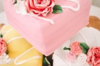 an assortment of mini wedding cakes – pink, yellow and white ones topped with pink sugar blooms is cool