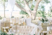 an elegant white spring wedding reception with greenery chandeliers, greenery runners, candles and gold pears