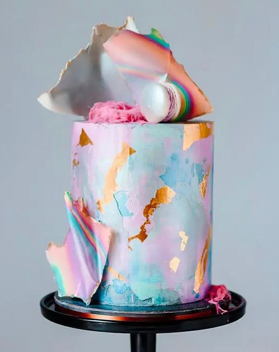 an iridescent wedding cake with pink, blue, turquouse brushstrokes and gold leaf, with shards and macarons on top