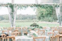 an outdoor-indoor spring wedding reception with pastel blue linens, white floral arrangements and greenery