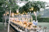an outdoor spring wedding reception with candle lanterns, greenery and pastel blooms