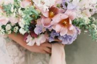 an oversized peachy, lilac and white wedding bouquet with greenery for a spring bride