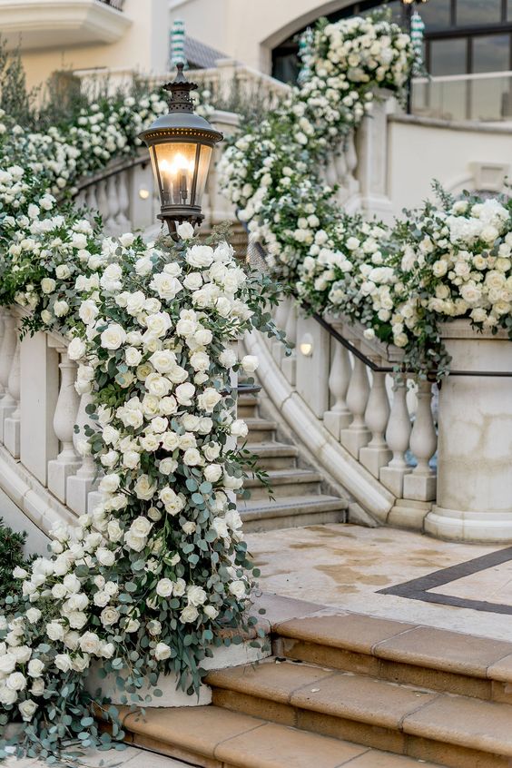 luxurious wedding staircase decor with lots of white roses and greenery is a lovely and cool solution to make a statement