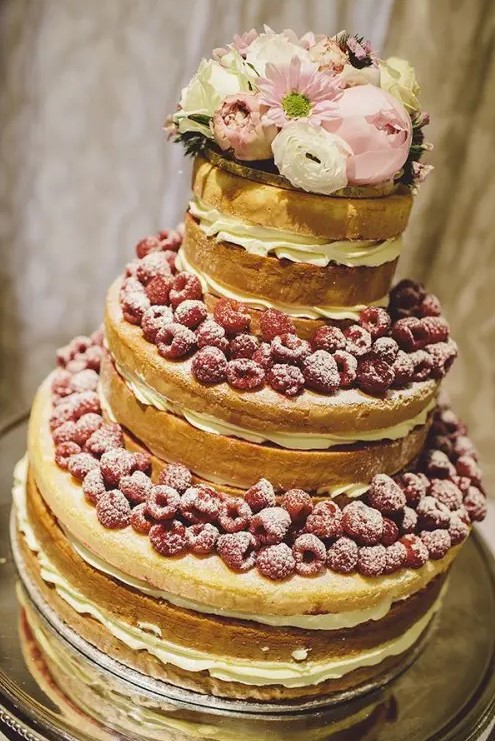 a naked wedding cake topped with berries, with blush and white blooms and greenery is a fantastic idea for a summer wedding