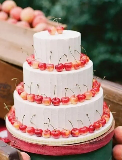 a white buttercream wedding cake lined up with cherries is a lovely idea for a summer wedding, it's cool and chic