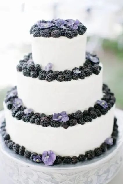 a white buttercream wedding cake topped with blackberries and pansies is a lovely idea for a chic summer wedding