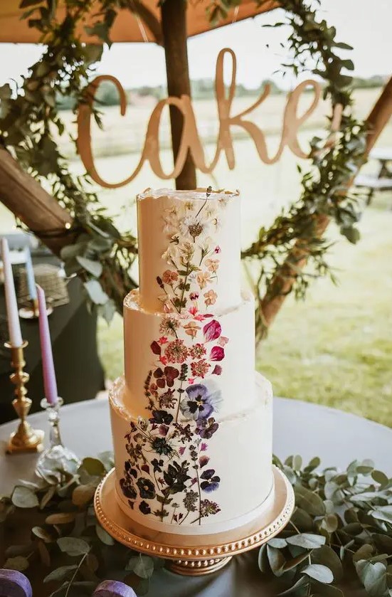 a white buttercream wedding cake with an ombre pressed flower pattern from purple to white is a lovely idea for a boho wedding