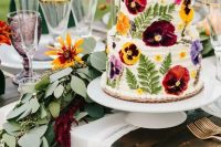108 a white buttercream wedding cake with pressed super bold red, yellow and purple blooms and leaves is a gorgeous idea for a summer wedding