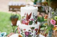 109 a white buttercream wedding cake with uneven edges and mustard, red and pink blooms and leaves pressed to it to form a pattern