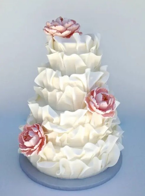 a white ruffle wedding cake with pink sugar blooms is a very creative and fun idea for a spring or summer wedding
