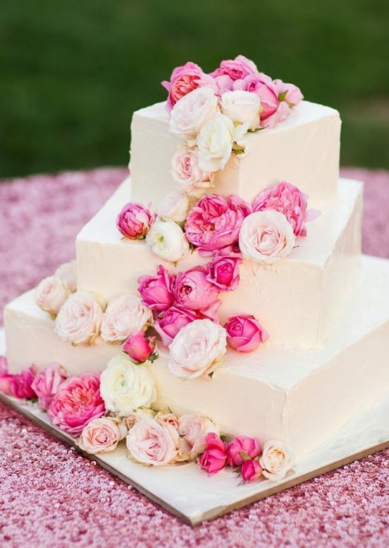 a white square wedding cake with pink and blush cascading blooms is a beautiful option for summer